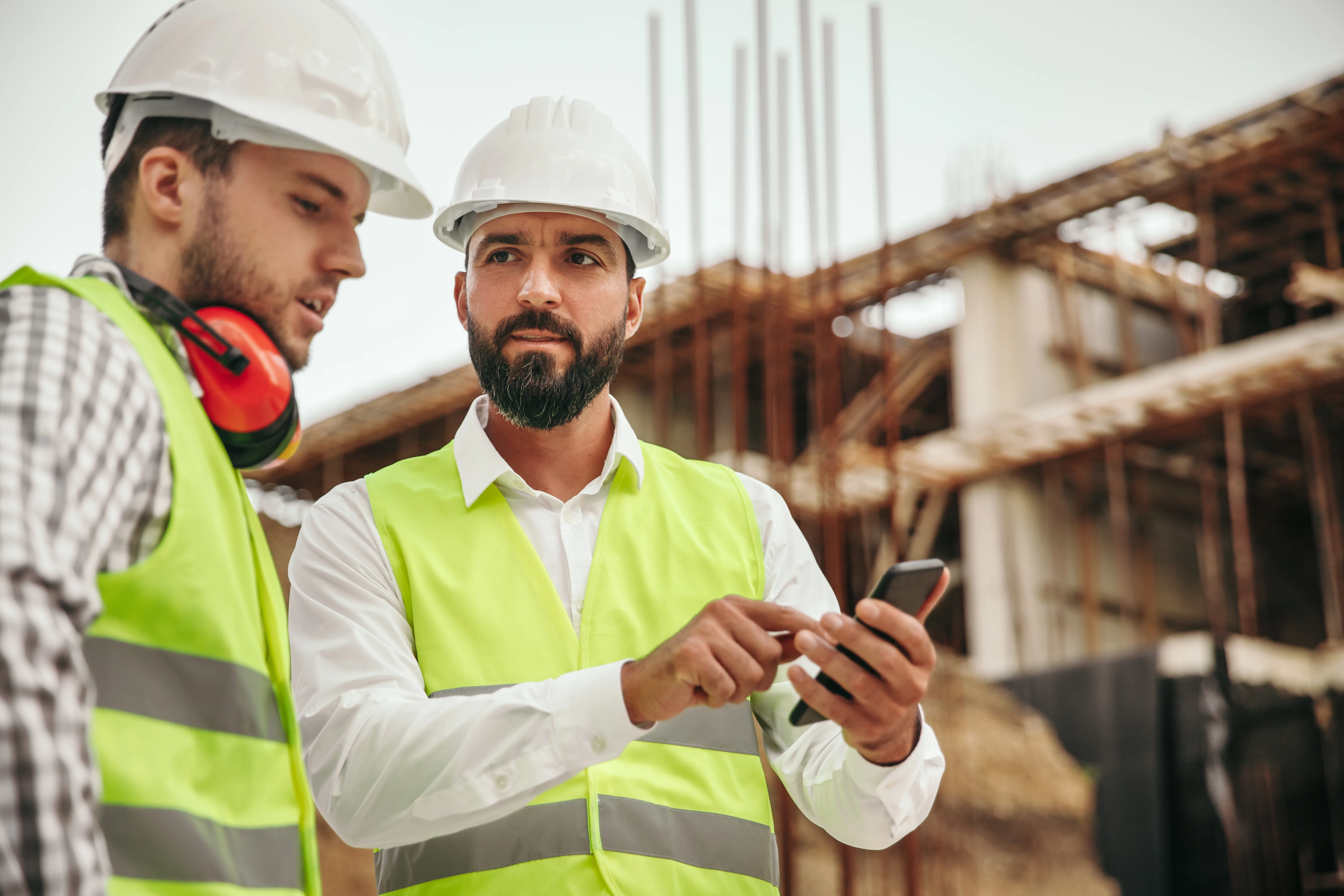Due uomini in cantiere guardano un cellulare